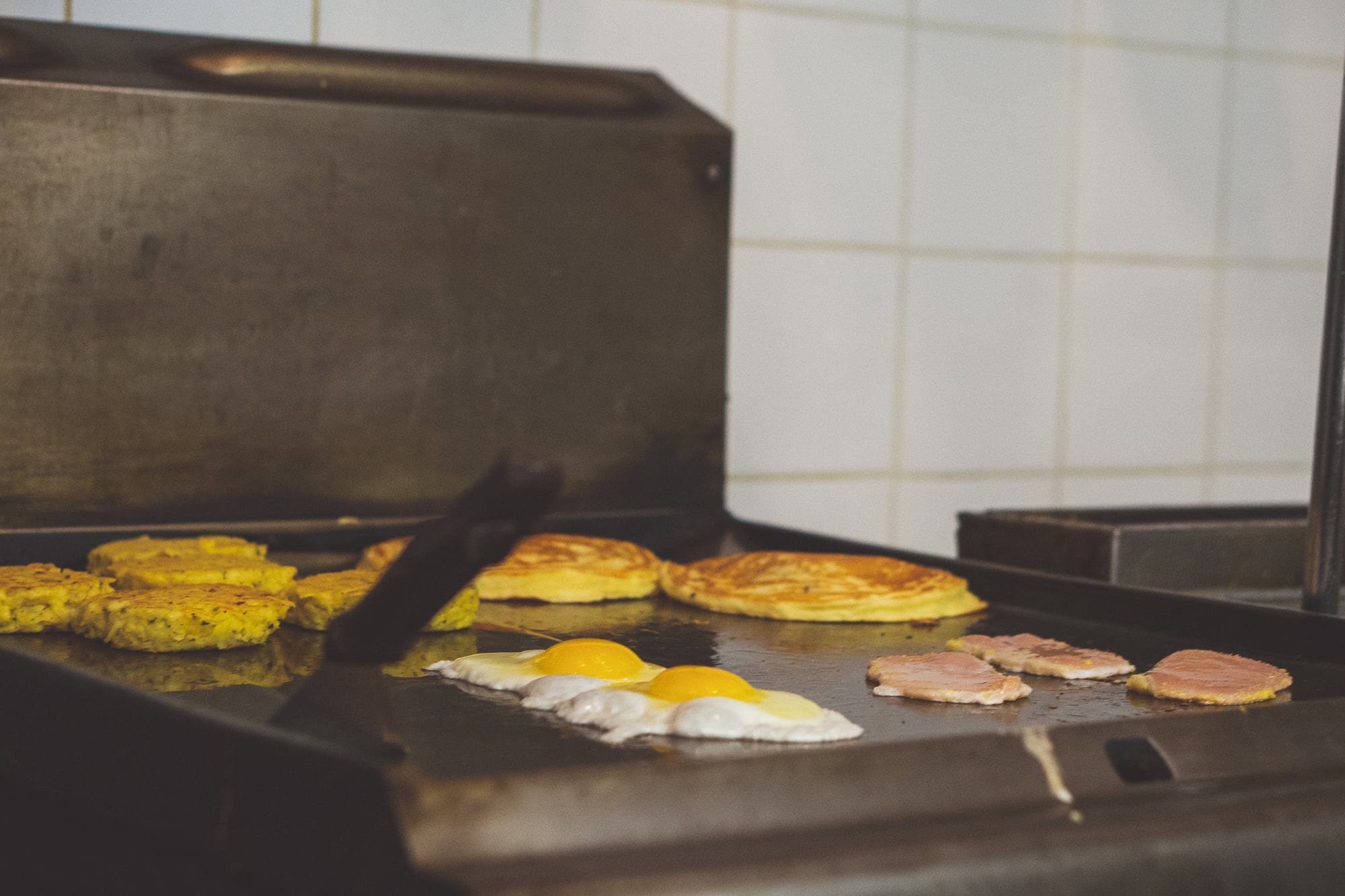 Eggs, pancakes and peameal bacon cooking on the flat-top grill